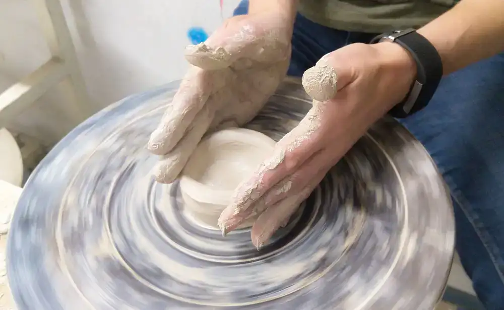 Hands shaping clay on a pottery wheel